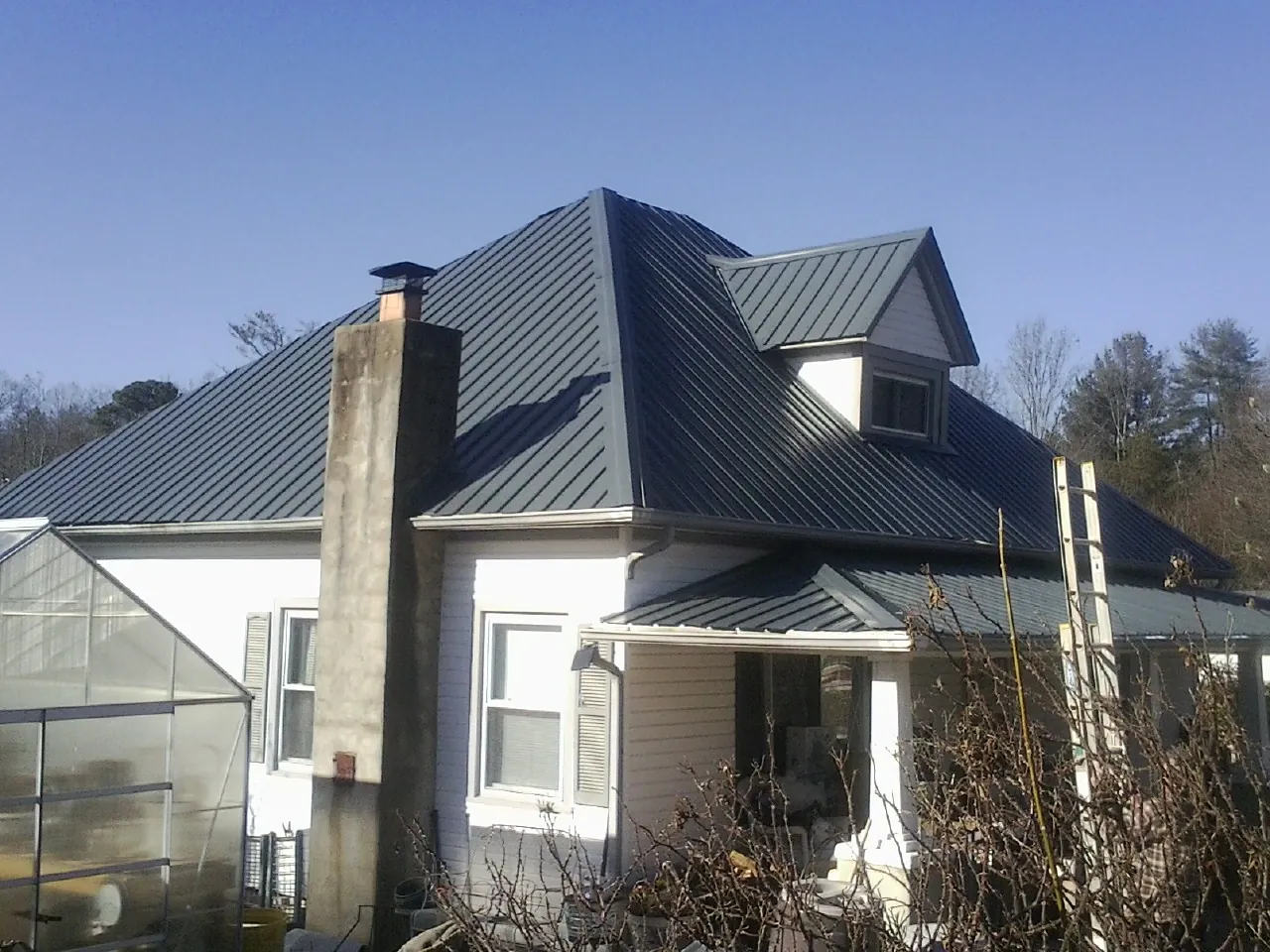 Dark blue standing seam metal roof on a white farmhouse with dormer — Slate & Tile Roof Repair by Roofing Brothers in Sayreville