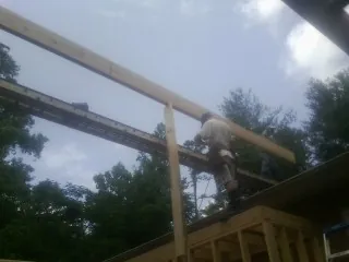 Carpenter setting a ridge beam over a new addition frame — Ice Dam Removal by Roofing Brothers in Sayreville