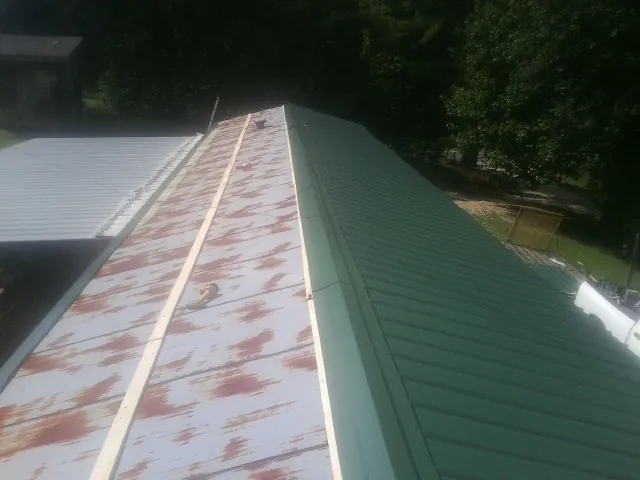 Old rusted panels beside newly installed green metal roofing — Wind Damage Roof Repair by Roofing Brothers in Sayreville