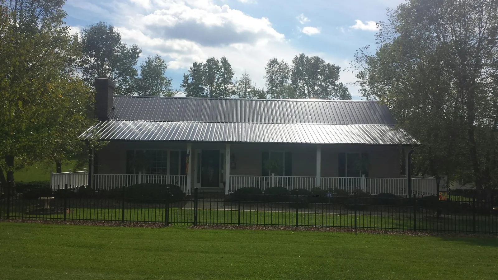 Gray metal roof on a brick ranch with a full width front porch — Gutter Guard Installation work by our crew in Sayreville