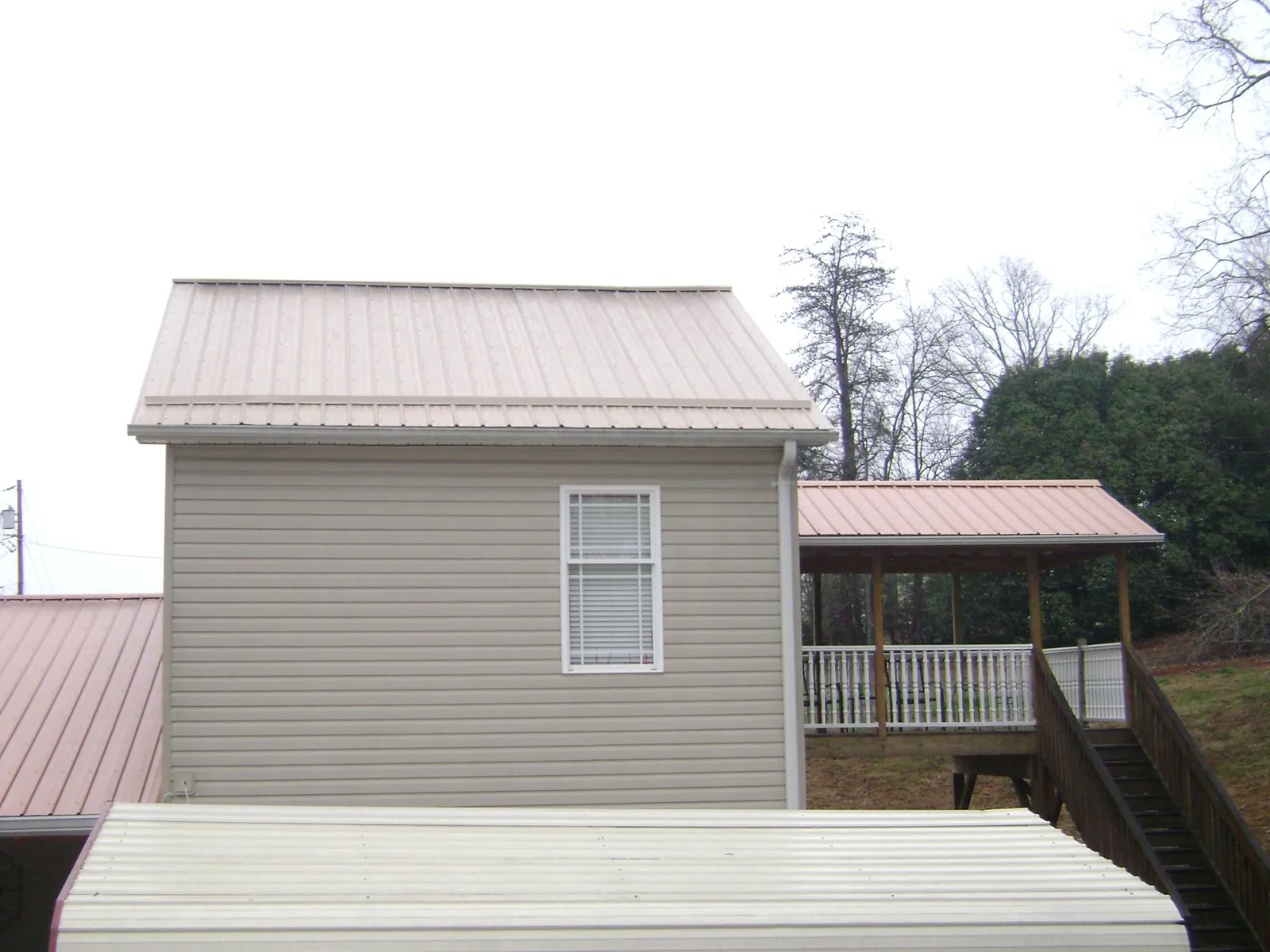 Tan metal roofs on a two story addition and attached porch, from a Roof Replacement job in Sayreville