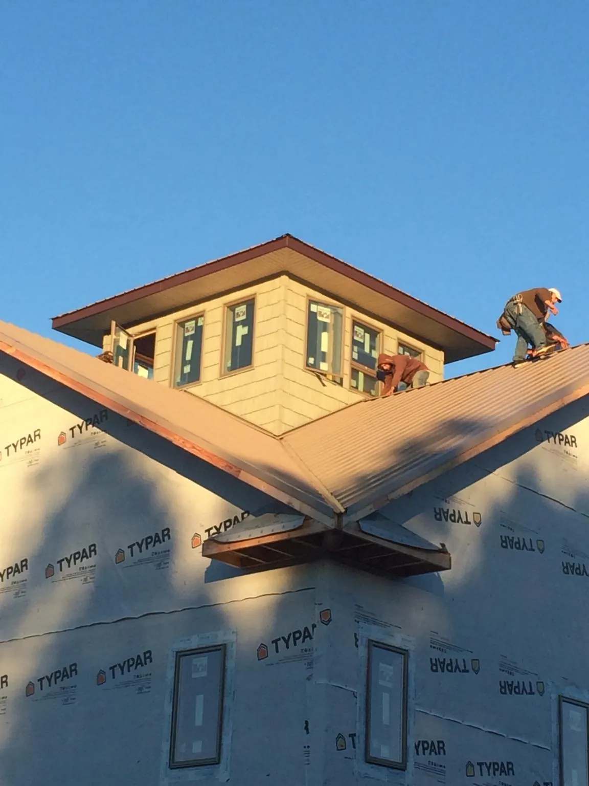 Roofers working around a rooftop cupola on a new metal roof at sunset — Roof Waterproofing in Sayreville by Roofing Brothers